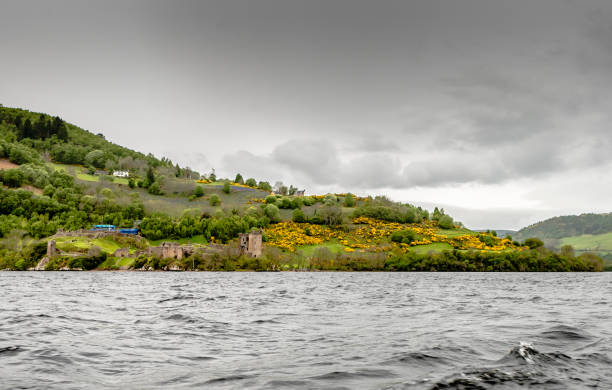 From a boat in Loch Ness - Ruins of a castle ruins of the beautiful Urquhart castle and the hills containing the castle taken during boat ride on the loch ness. While the castle is beautiful, it is minuscule in the overall context of the lake and the hill. drumnadrochit stock pictures, royalty-free photos & images