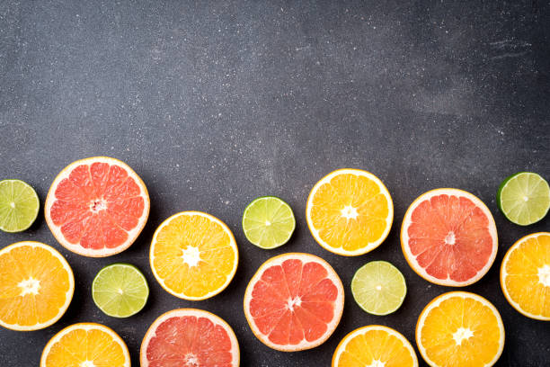 istock Half of citrus fruits on dark stone background 698012978