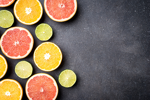 Half of citrus fruits on dark stone background. Top view