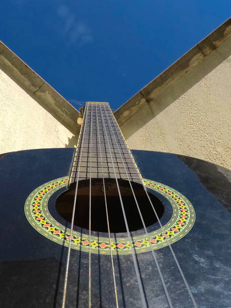 Guitar and Sky Closeup of a guitar leaning against a wall with the sky in the background música stock pictures, royalty-free photos & images