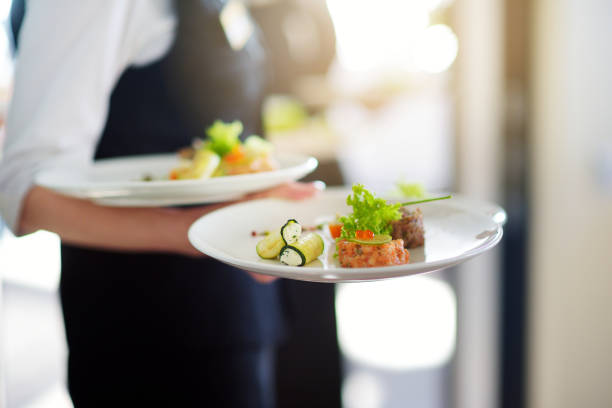 cameriere che porta piatti con piatto di carne in qualche evento festivo - waiter foto e immagini stock