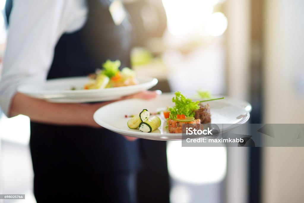 Waiter carrying plates with meat dish on some festive event Waiter carrying plates with meat dish on some festive event, party or wedding reception Restaurant Stock Photo