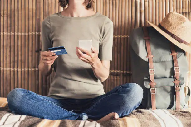 Young woman on vacations using phone and credit card. Online shopping concept