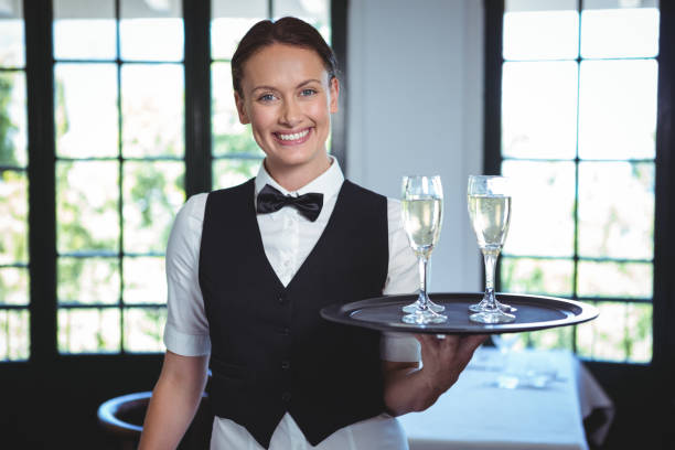 camarera con una bandeja de la flauta de champagne - hotel restaurant women luxury fotografías e imágenes de stock