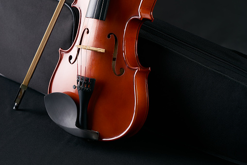 Classical wooden Violin with molded carrying black case. Musical string instrument fiddle with violin bow isolated on black background.