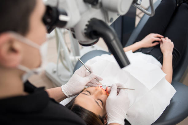 istock Male dentist with dental tools - microscope, mirror and probe checking up patient teeth at dental clinic office. Medicine, dentistry and health care concept. Dental equipment 698031040