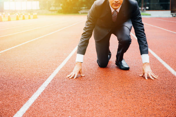 Business man preparing to run on the competition running track Business man preparing to run on the competition running track starting line stock pictures, royalty-free photos & images