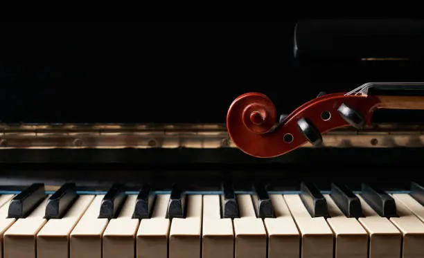 Photo of Classical musical stringed instrument violin on piano keys.