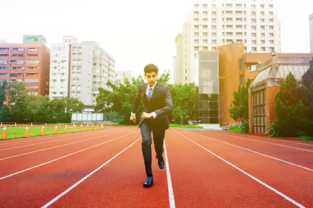 Photo of Male determined businessman running on performance race track - challenge and competition concept