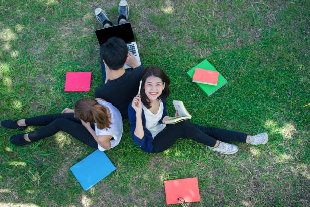 istock Young Students Group Smiling with Folders Book and Laptop computer Smiling on Grass in Education Campus University Top view 698048096