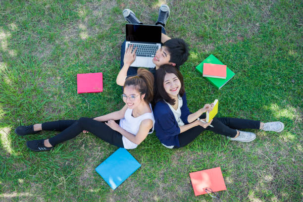 istock Young Students Group Smiling with Folders Book and Laptop computer Smiling on Grass in Education Campus University Top view 698048294