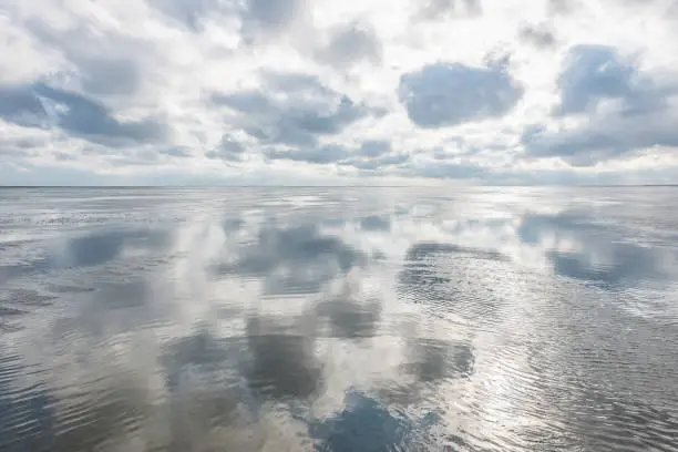 Clouds are reflected in the water on the mudflats of the North Sea