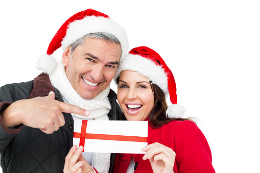 Festive couple pointing christmas gift on white screen