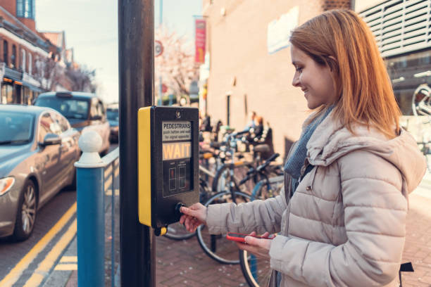 улыбающаяся женщина, нажимающая кнопку стоп-сигнала на пешеходной дорожке - london england england street light telephone стоковые фото и изображения