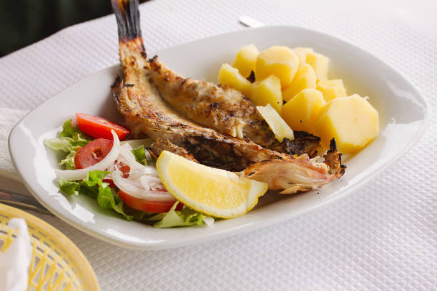 grilled fish with vegetables on white dish in restaurant