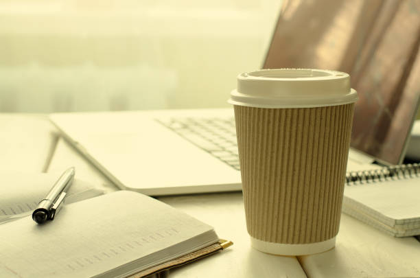 istock Paper cup of coffee on work-table with office stuff, notepad, laptop, pen and coffee cup 698068338