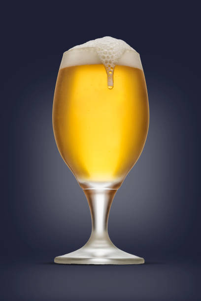 istock Glass of beer with foam falling, isolated on blue background. 698069438