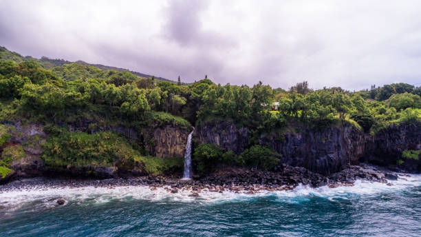 cascate che scendono a cascata lungo le scogliere sull'oceano pasific, hawaii - waterfall maui hana coast hawaii islands foto e immagini stock