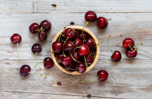 Red cherries in a bowl on a old wooden background