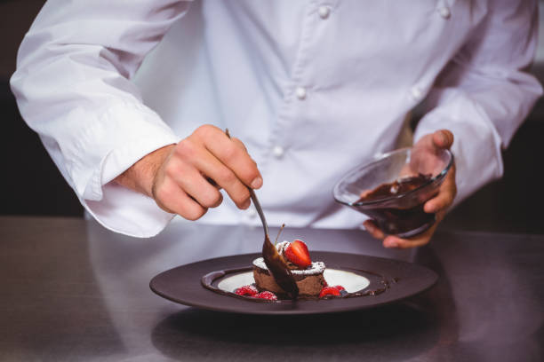 Chef putting chocolate sauce on a dessert in a commercial kitchen