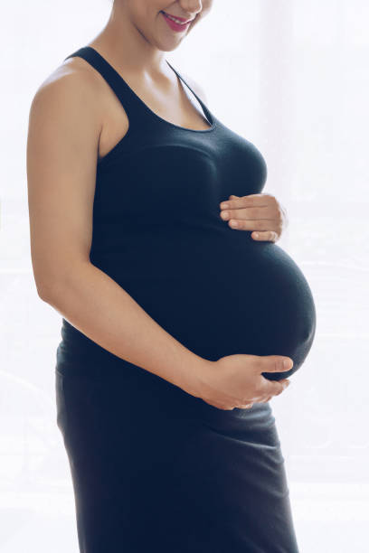 istock Pregnant woman standing against the window 698083696