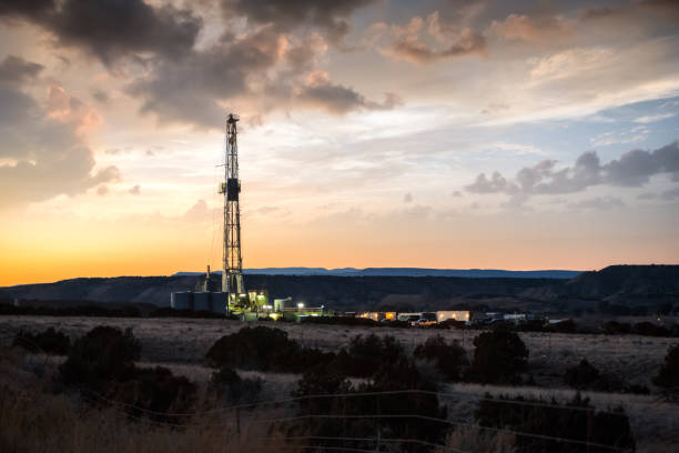 아름 답게 극적인 일몰 하늘 아래 fracking 드릴 장비를 점등 - sunset oil rig oil industry energy 뉴스 사진 이미지