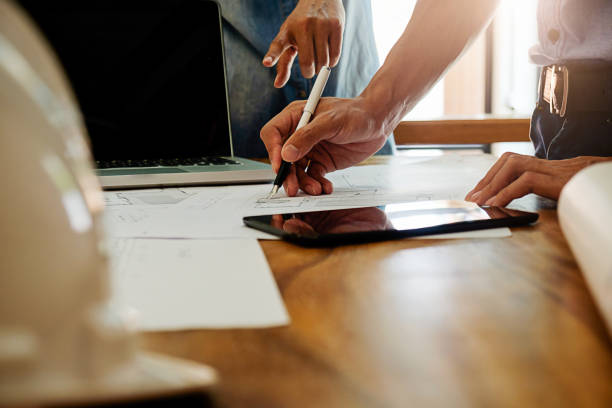 istock Architects engineer discussing at the table with blueprint - Closeup on hands and project print. 698095122