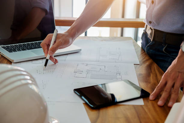istock Architects engineer discussing at the table with blueprint - Closeup on hands and project print. 698095148
