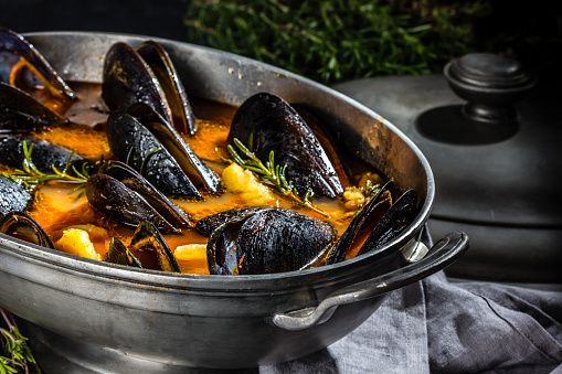 Seafood  mussels soup in metal vintage pot on gray slate background