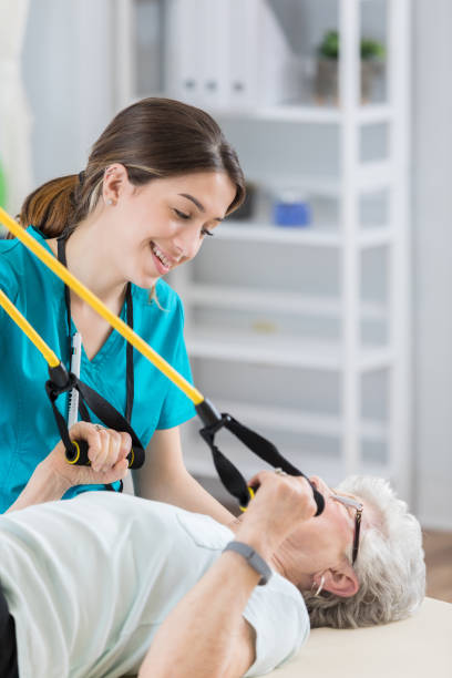 istock Attractive young nurse assists senior in using exercise bands 698107848
