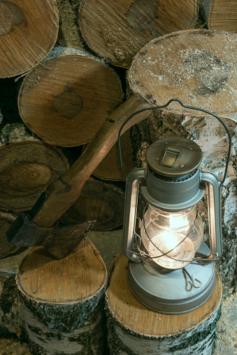 oil lamp, an ax and birch firewood stacked in a barn
