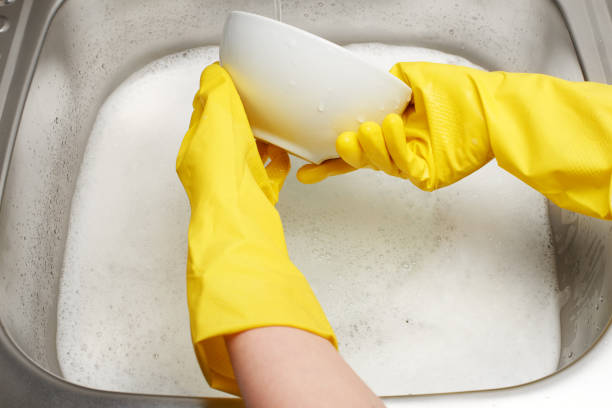 istock Hands in gloves washing white bowl under running tap water 698113854