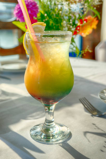 istock Alcohol cocktail glass layered with lemon and with two tubes worth on the table 698117170