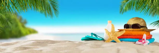 Tropical beach with sunbathing accessories, summer holiday background. Travel and beach vacation, free space for text.