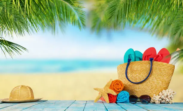 Tropical beach with sunbathing accessories placed on blue wooden planks, summer holiday background. Travel and beach vacation, free space for text.