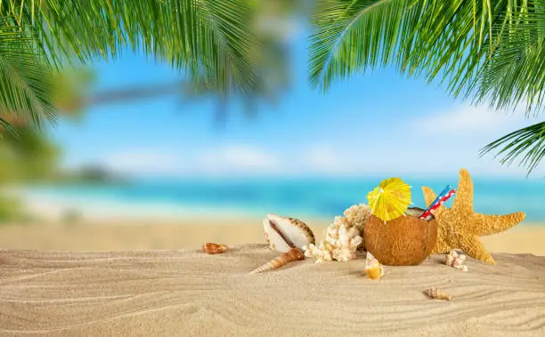 Tropical beach with sea star and coconut drink on sand, summer holiday background. Travel and beach vacation.