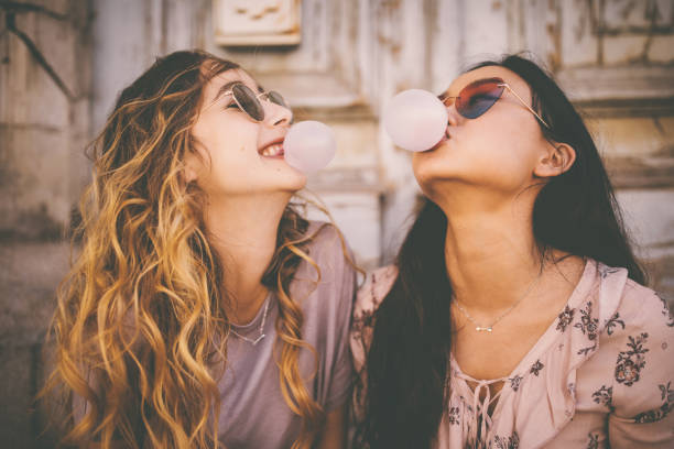 istock Young women blowing bubbles with bubble gum in urban setting 698124258