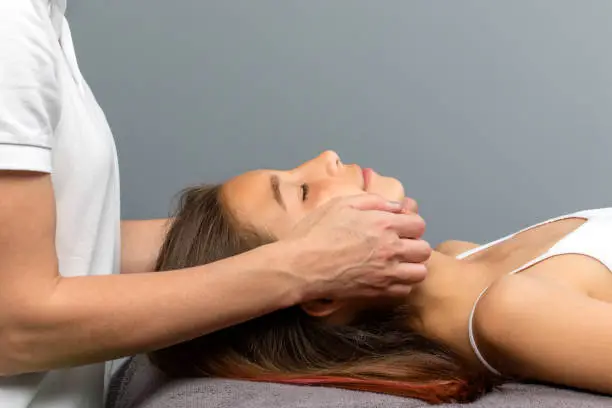 Close up of therapist doing osteopathic treatment on little girls chin.