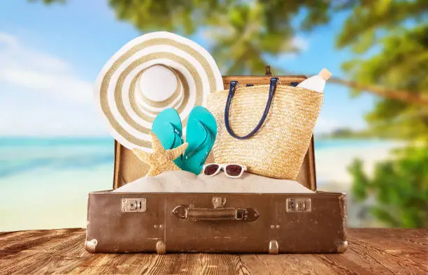 Retro luggage with summer beach holiday accessories placed on wooden planks. Concept of summer vacation and travelling.