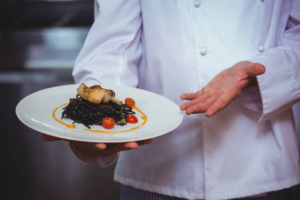 istock Proud chef holding a plate of squid ink spaghetti 698126840