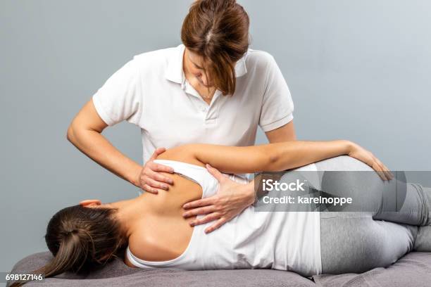 Female Therapist Manipulating Shoulder Blade On Young Female Patient Stock Photo - Download Image Now