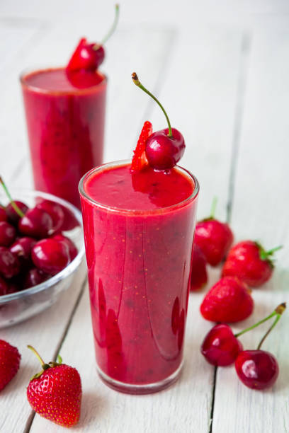 cherry and strawberry smoothie and berries on white table. fresh natural milkshake - vitality food food and drink berry fruit imagens e fotografias de stock