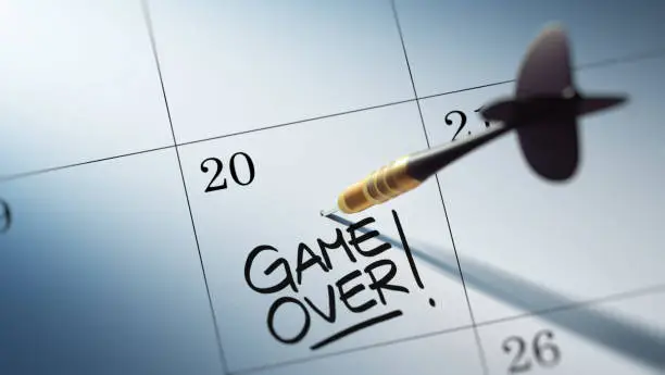 Concept image of a Calendar with a golden dart stick. The words Game over written on a white notebook to remind you an important appointment.