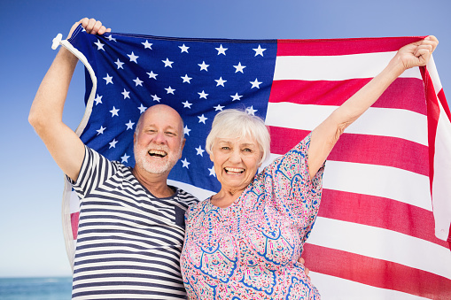 Senior couple holding american flag on a sunny day