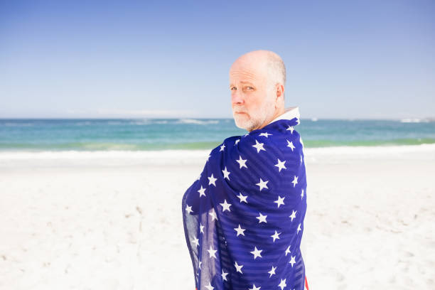 Senior man holding american flag on the beach