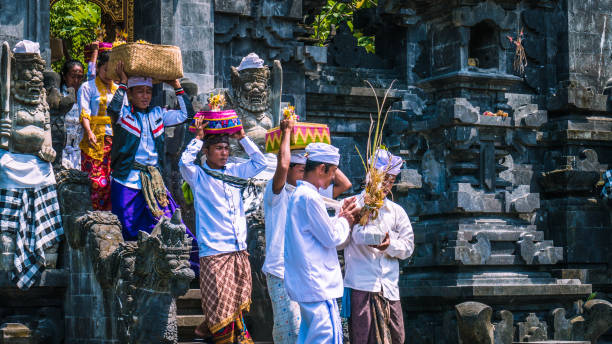 balijczycy w tradycyjnych ubraniach noszą pobłogosławić prezent po ceremonii w świątyni pura goa lawah, bali, indonezja - pura goa lawah zdjęcia i obrazy z banku zdjęć