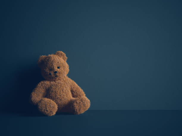 Child abuse concept Teddy bear with torn eye sits in dark room. Child abuse and violence concept. child crimes stock pictures, royalty-free photos & images
