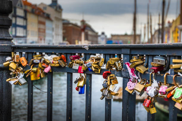 istock Colourful padlocks hanging from bridge with city in background 698202822