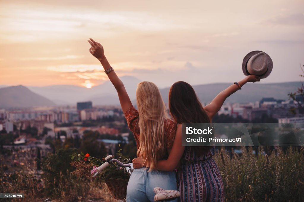 Breath the life Two awesome girls cheering life in front of the sunset Friendship Stock Photo