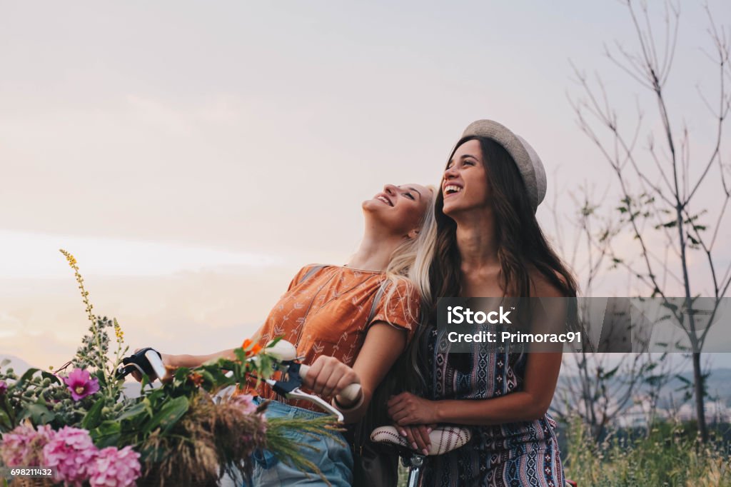 Two girls enjoy bike and great day Two beautiful girls with bike smiling on a grat day Springtime Stock Photo